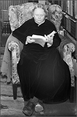 Foto av Maria Qvist Månsson på gamla dar, hon sitter i en fåtölj med bene utsträckta framför sig och läser