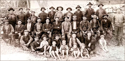 Foto av en mängd män och barn som står eller sitter utomhus