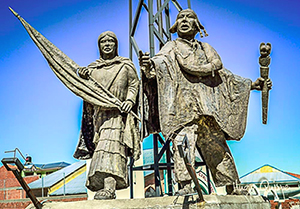 Foto av staty med Bartolina Sisa och hennes man mot blå bakgrund