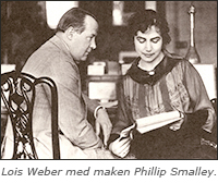 Foto av Lois och Smalley sittande bredvid varandra, hon läser ur några papper hon håller i handen