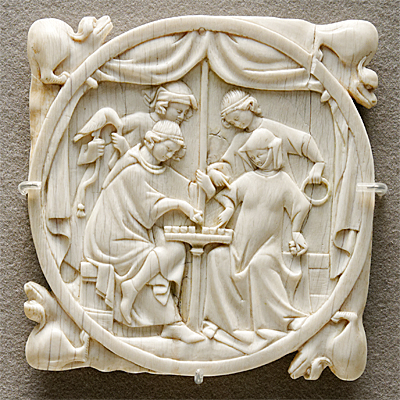 En vit, rund relief där en man och en kvinna spelar schack medan två andra tittar på