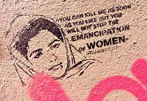 Graffiti-vägg med en bild av en kvinna i sjal och texten: You can kill med as soon as you like but you will not stop the emancipation of women. Táhirih 1852