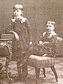 Foto av Märta och Elisabeth Tamm 1883. Märta står lutad mot ett bort, tre-åriga Elisabeth sitter på en stol bredvid.