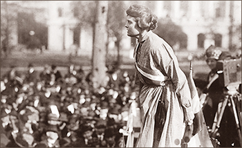 Foto av en kvinna som står och talar framför en folkmassa