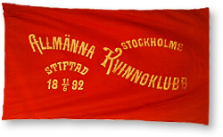 Foto av en röd fana med gul text, där det står: Stockholms Allmänna Kvinnoklubb, stiftad 11/6 1892