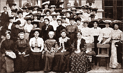 Foto av en stor mängd kvinnor som sitter respektive ståri fyra rader bakom varandra. Många har hattar