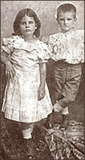 Foto av en flicka och en pojke som står avslappnat ochser in i kameran