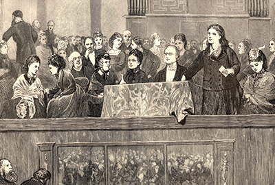 Illustration av Rhoda Garrett hållande tal stående vid ett bord med duk vid ett möte 1872 omgiven av andra dåtida feminister som sitter runt omkring henne