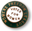 Rockmärke i vitt, grönt och guld, som det står "Votes for Women" mitt i, omgivet av "Women's Freedom League"