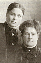 Porträttfoto av Anna och Lydia, bägge i höghalsade blusar och uppsatt hår
