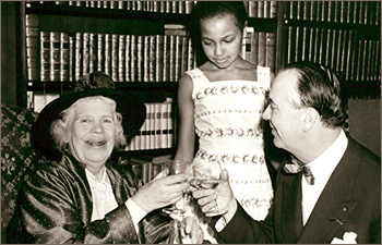 Foto av en skrattande Amelie Posse som skålar med Carl Gerhard medan hans dotter Fatima tittar på