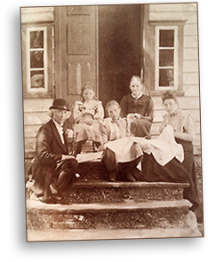 Foto av Ottar och en del av hennes familj sittande på trappan till deras hus