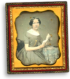 Gammaldags daguerreotyp i en utsmyckad ram i guld, gult och tegelrött. Inuti ett färglagt foto av Rosalie som ung kvinna som sitter och läser med en bok i handen. Hon ser rakt in i kameran