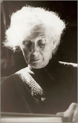 Porträttfoto av vithårig äldre Vera Nilsson som ser ner mot något framför henne