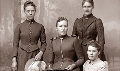 Studiofoto av fyra kvinnor som ser ganska finklädda ut och med håret tjusigt uppsatt
