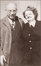 Foto i halvfigur av Joe Shavelson och Clara Lemlich på äldre dar. De står utomhus, bägge har glasögon på sig och de ser in i kameran och ler