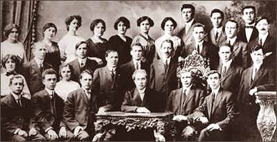 Foto av 19 män och 9 kvinnor som sitter och står i fyra rader bakom varandra. Männen har kostym och slips. Alla ser in i kameran