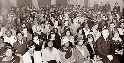 Foto av en jättestpr sal fylld med massor av folk, mest svarta och i alla fall i förgrunden mest kvinnor.