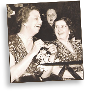 Foto av medelålders Eleanor Roosevelt och Rose Sneiderman i halvfigur iklädda sommarklänningar. Eleanor skrattar högt, medan Rose ser roat på henne. Rose har glasögon på sig.