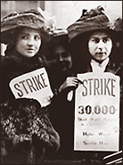 Foto av två kvinnor som håller upp plakat som det står "STRIKE 30.000" på + en del mer som är oläsligt. Det är vinter, de har tjocka kläder och stora hattar på sig