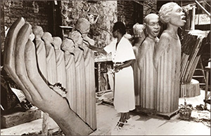 Foto av en kvinna mitt i bild som arbetar på ett framväxande verk av sjungande svarta och en stor hand
