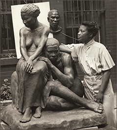 Foto av Augusta Savage, utomhus, vid en av sina skulpturer av en kvinna och en man