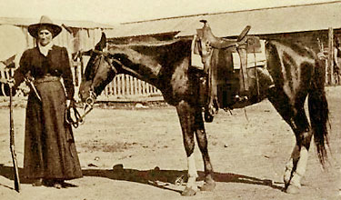 Foto av Calamity Jane med sin häst och sitt gevär