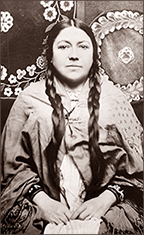 Foto i halvfigur av Bottineau Baldwin som sitter iförd traditionell klädsel och ser rakt in i kameran
