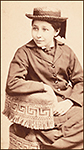 Susan La Flesche som barn iförd en hatt och jacka, sittande på en stol