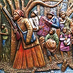Målad trärelief där Harriet Tubman går i förgrunden och flera människor går bakom henne i en skog