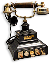 Foto av gammaldags telefon  med diverse soakar, det står "Stockholms Telefon" mitt på med guldbokstäver