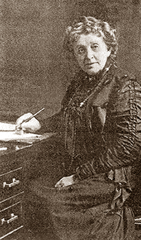Foto av Josephine Garis Cochrane som äldre, sittande vid sitt skrivbord med en penna i handen