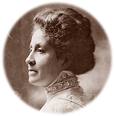 Porträttfoto av Mary Church Terrell i profil med håret uppsatt i en tjusig frisyr. Hon har en höghalsad klänning med mycket spetsar på sig