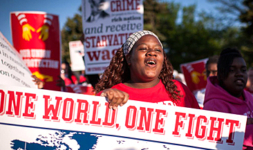 Foto av en leende tjej som håller i ett stort plakat med rubriken: One World, One Fight