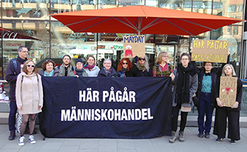 Foto av en samling kvinnor med många plakat och en banderoll med texten "Här pågår människohandel"
