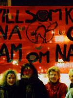 Foto av kvinnor framför en röd banderoll på natten
