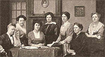Foto av sju kvinnor som sitter och står runt ett bord
