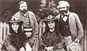 Foto av Friedrich Engels och Karl Marx stående bakom de sittande tre flickorna utomhus framför ett ljust staket